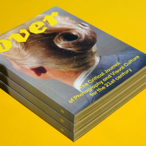 Three stacked magazines showing the cover of OVER Journal on a yellow background.